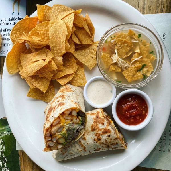 Two burritos, a pile of tortilla chips, chicken tortilla soup, salsa, and ranch dressing.